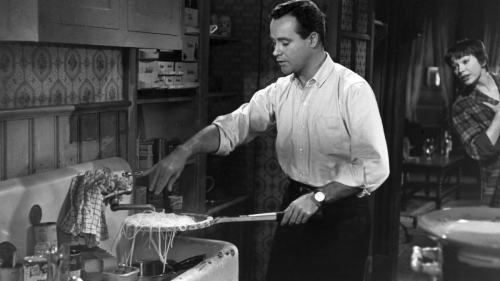 In the apartment’s kitchen Baxter demonstrates his culinary talent, draining the spaghetti onto a tennis racquet before serving it with meatballs. Fran is on the threshold of the kitchen. ‘The Apartment’ directed by Billy Wilder © 1960 Metro-Goldwyn-Mayer Studios Inc. All rights reserved.
