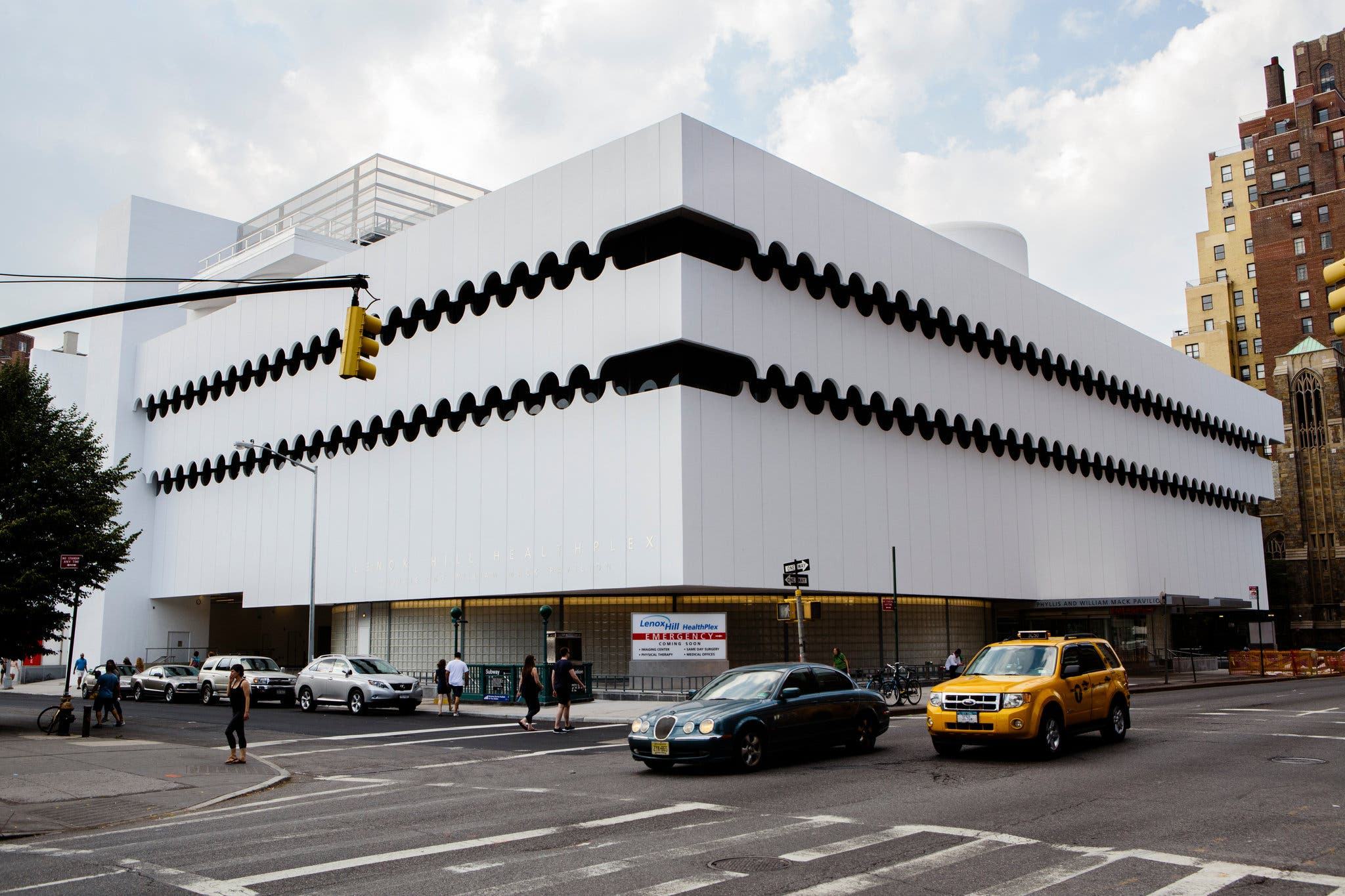 Exterior view of St. Vincent's Hospital. Low-rise white building on 7th Avenue with a few cars in front.