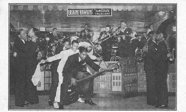 A black and white photograph of a band performing. A man playing the upright bass is in the center, playing the instrument bending over between his legs. Two couples dance together on opposite sides of the photo frame